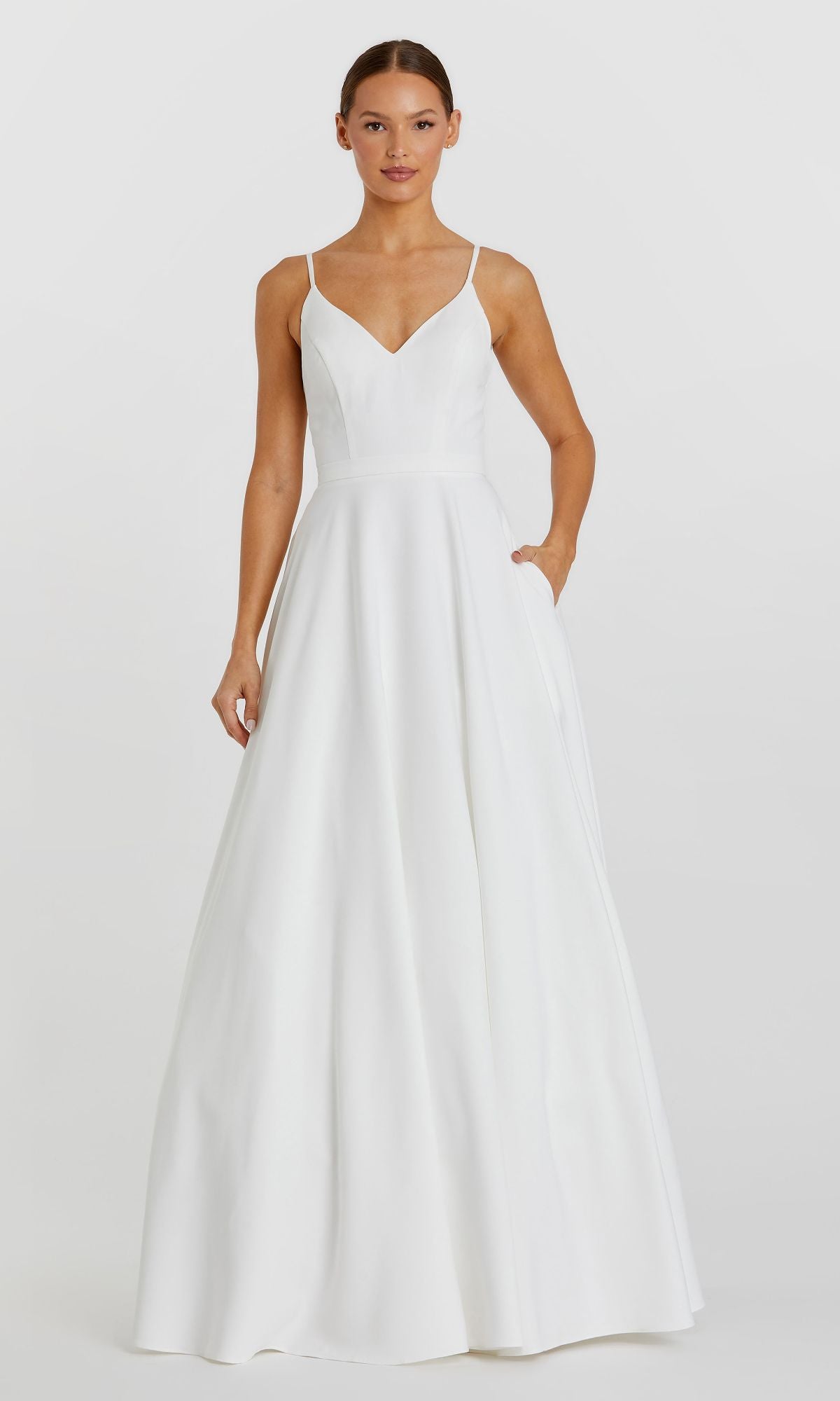 A woman poses against a plain light background, wearing the Classic Long A-Line Formal Dress: Mac Duggal 48855—a sleeveless white gown with thin straps and pockets.